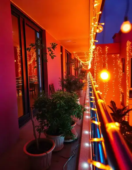 Diwali balcony decorated with warm string lights and potted plants | Vibrant Balcony Diwali Light Decoration | Balcony Diwali Lighting | Decorations Guru